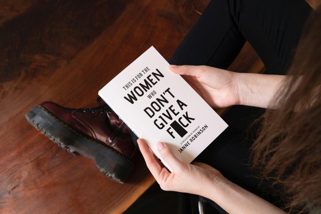 A woman sits holding an empowering book, promoting feminism and empowerment.
